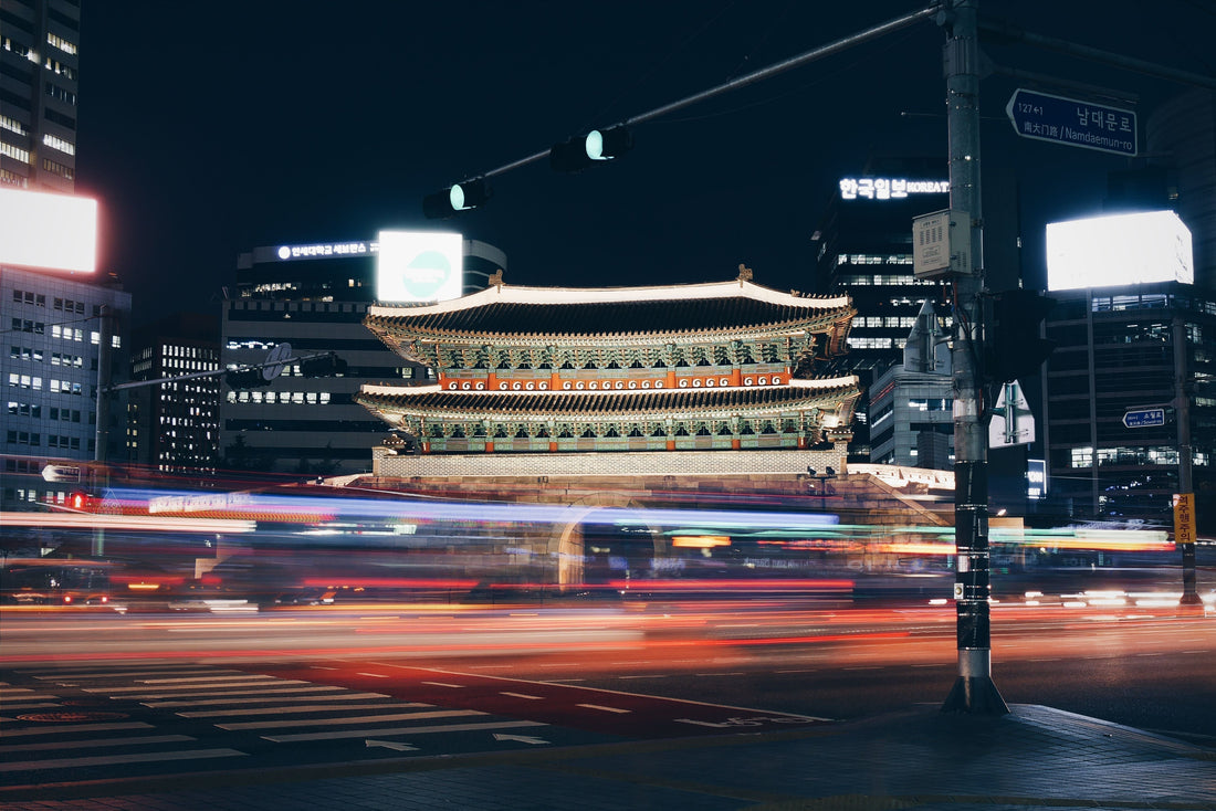 Porte Sungnyemun illuminée de nuit, entourée d’immeubles modernes et de circulation à Séoul